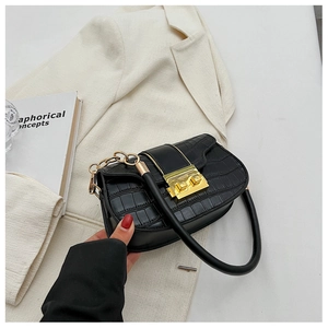 Close-up of black crocodile leather texture with gold square lock and chain detail