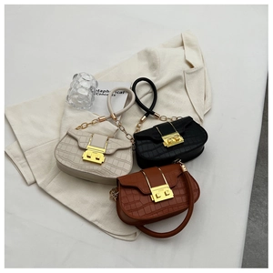 Three crocodile embossed saddle bags in cream, black, and brown with gold hardware