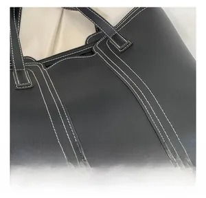Close-up of black lychee grain leather tote bag with white contrast stitching detail