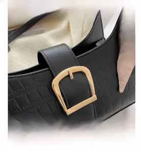 Close-up of black crocodile embossed bag with gold horseshoe clasp and decorative scarf