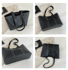Detail view of black tote bag with white contrast stitching and long shoulder straps
