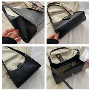 Detail view of black crocodile pattern underarm bag with gold buckle and silk scarf