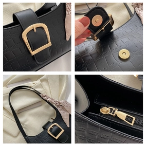 Detail of black crocodile texture bag featuring gold buckle and silk scarf handle accent