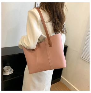 Detail of pink tote bag with white contrast stitching and brown leather shoulder strap