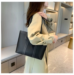 Detail of large black tote bag with white contrast stitching and long shoulder straps