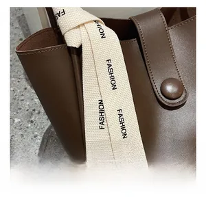 Détail d'un sac cabas en cuir marron foncé avec un foulard en soie décoratif imprimé