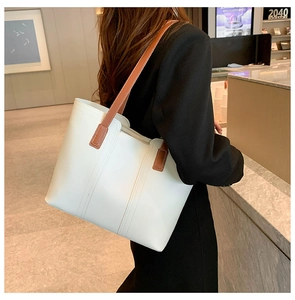 Detail of a large white vintage tote bag with slim brown straps in a lifestyle bookstore setting