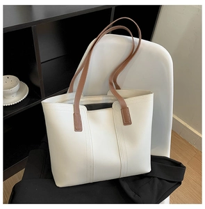 Detail view of cream white tote bag with brown straps and fine stitching for daily commute