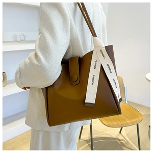 Détail d'un sac cabas en cuir marron avec ruban tendance et rabat à boucle décorative