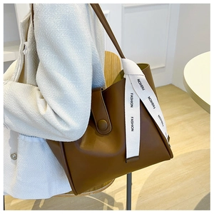 Détail du sac cabas en cuir marron avec sangle décorative et boucle de fermeture élégante