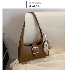 Detail of khaki crocodile pattern shoulder bag with golden buckle and floral scarf