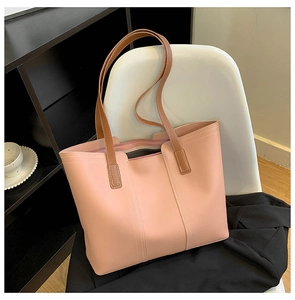 Detail view of pink tote bag with brown straps and multi-compartment interior on a chair