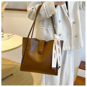 Détail du sac cabas en cuir marron avec fermoir magnétique et ruban décoratif fashion