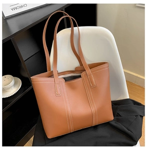 Close-up of vintage brown tote bag featuring white contrast stitching on leather surface