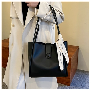 Détail d'un sac cabas en cuir noir avec un foulard décoratif en soie beige