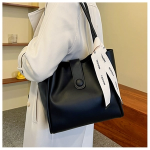 Détail du cabas en cuir PU noir avec ruban mode et fermeture par bride latérale lisse