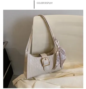 Detail of white crocodile texture leather bag with gold buckle and silk scarf accent