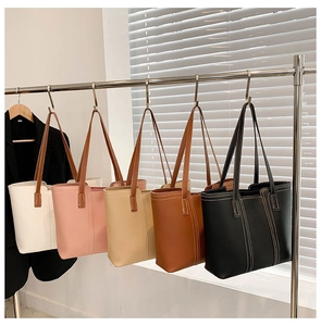 Row of large vintage tote bags in five colors hanging on a metal rack for display
