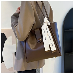 Vue détaillée du sac cabas en cuir marron avec un ruban décoratif à la mode