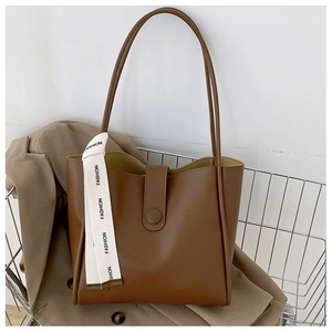 Gros plan d'un sac cabas marron avec étiquette mode et fermoir pression dans un panier