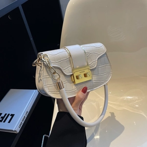 White croc-effect crossbody bag with gold chain and metal lock held in lifestyle setting