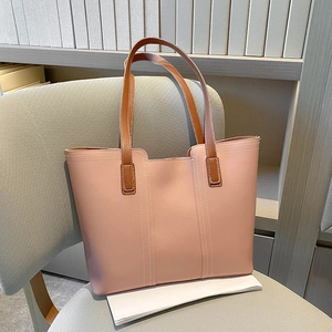 Pink leather tote bag with brown straps and white stitching on a grey chair