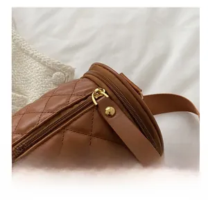 Détail de la fermeture éclair dorée et de la texture en cuir matelassé marron du sac