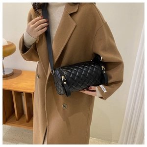 Détail du sac cylindrique noir matelassé avec bandoulière large et finitions dorées