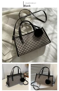 Detail of black and white houndstooth handbag with plush ball charm and leather strap