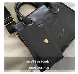 Détail du sac en cuir verni noir avec mini pochette et lettrage doré élégant