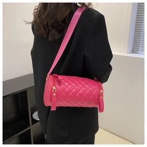 Détail du sac cylindrique matelassé rose rouge avec large bandoulière et métal doré