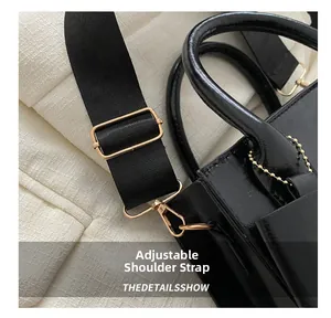 Détails de la bandoulière en nylon réglable et ferrures dorées sur un sac à main noir brillant