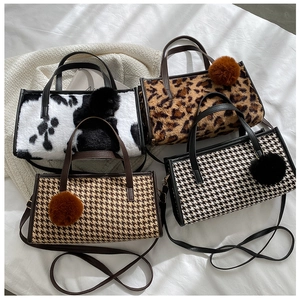 Detail of four faux fur tote bags in cow, leopard, and houndstooth prints with pom-poms