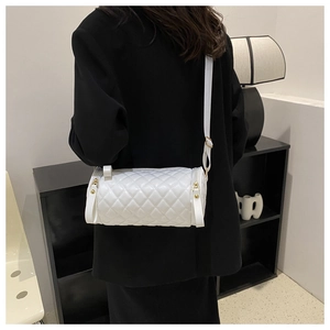 Vue détaillée du sac cylindrique matelassé blanc avec large bandoulière et métal doré