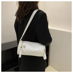 Sac cylindre blanc matelassé avec bandoulière large porté par un mannequin de mode