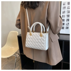 Detailed shot of white quilted chain bag with woven handle worn by a model