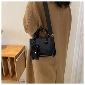 Détail du sac bandoulière en cuir noir brillant avec porte-monnaie et sangle large