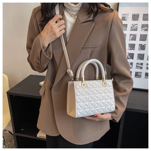 Detail showing white quilted crossbody bag with woven handle and gold hardware links