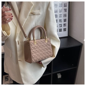 Detail of pink quilted crossbody bag with woven handle and adjustable strap on a white blazer
