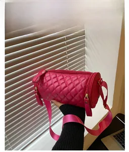 Détail du sac cylindrique matelassé rose avec large bandoulière en nylon et zip