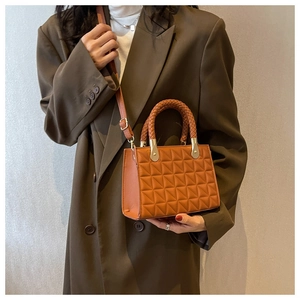 Detail of brown leather handbag with geometric triangle texture and woven handle on a model