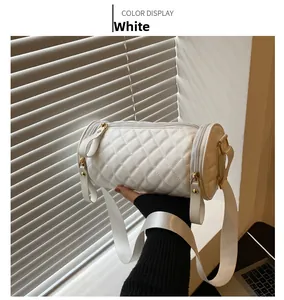 Détail du sac cylindrique blanc matelassé avec bandoulière large et boucles dorées