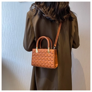 Caramel brown crossbody bag featuring woven handle and quilted texture shown on a model