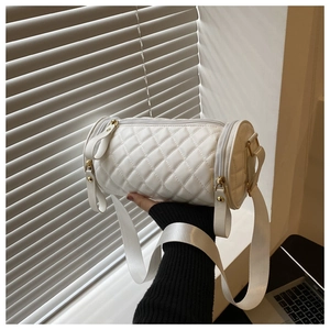 Détail du sac cylindrique matelassé blanc avec ferrures dorées et large bandoulière
