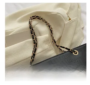 Close-up of black crocodile pattern leather texture with metal chain strap detail