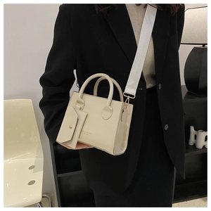 Détail d'un mini sac cabas crème avec large bandoulière et petit pendentif enveloppe
