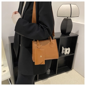Détail d'un sac à main marron mat avec bandoulière large et mini porte-monnaie attaché