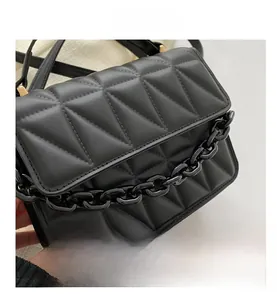 Detail view of black quilted faux leather crossbody bag with chunky chain and gold hardware