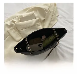Flat lay of black leather tote bag interior showing capacity for umbrella and cosmetics