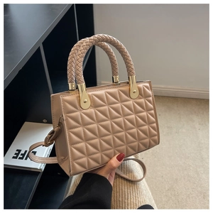 Detail of quilted texture and woven top handles on a nude pink crossbody bag